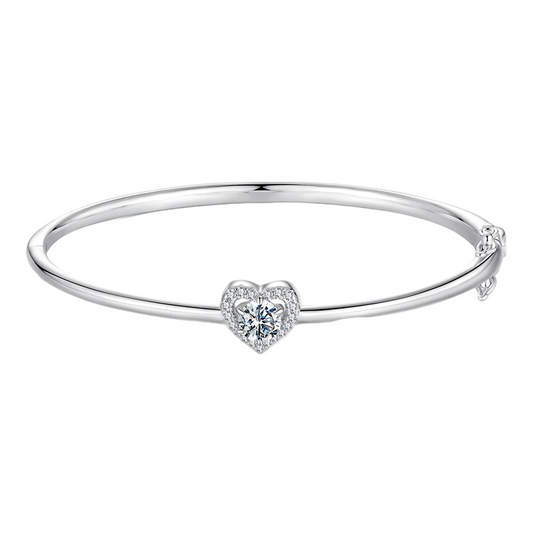 Silver bangle with a heart-shaped diamond on a white background